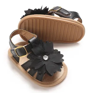 Detalle de sandalias de verano para bebé con flor negra y suela de goma antideslizante