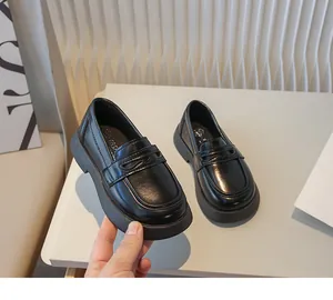 Gedetailleerd overzicht van zwarte loafers voor jongens in Britse stijl met platte zool