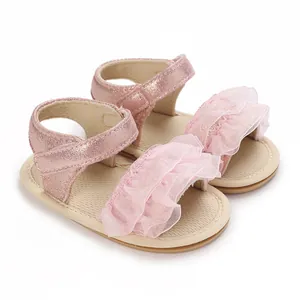 Primo piano di sandali rosa per neonata con volant in pizzo decorativo e cinturini metallici