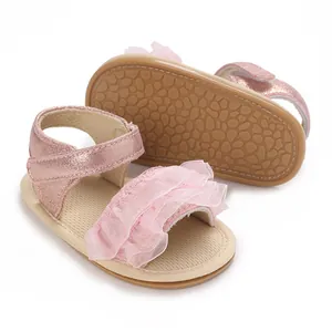 Dettaglio di sandali rosa per neonata con cinturino metallico e suola in gomma antiscivolo.