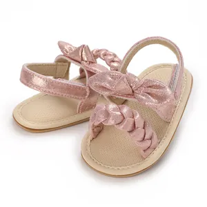 Close-up of pink glitter baby sandals with bow and braided strap detail
