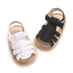 Paio di sandali estivi per neonati con suola morbida e design intrecciato bianco e nero.