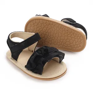 Dettaglio di sandali neri per neonata con suola in gomma morbida e pizzo elegante