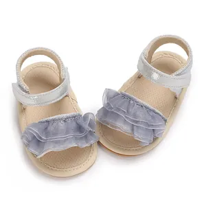 Dettaglio di sandali per neonata con cinturini argentati e tessuto a balze viola