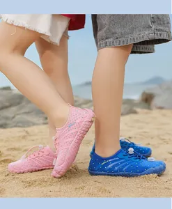 Nahaufnahme von pinken und blauen Wasserschuhen für Kinder am sonnigen Sandstrand