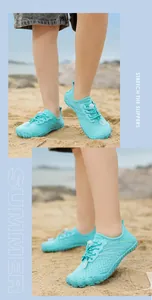 Detailansicht von türkisfarbenen Kinder-Wasserschuhen an einem sonnigen Sandstrand