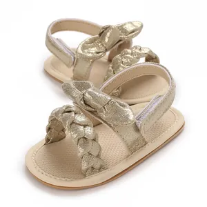 Glittery gold baby girl sandals with braided straps and bow details for toddlers.