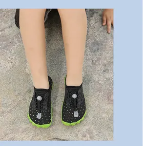 Detailansicht atmungsaktiver Kinder-Wasserschuhe mit grüner rutschfester Sohle auf Fels.