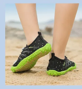Rückansicht atmungsaktiver Kinder-Wasserschuhe mit grünen Sohlen am Sandstrand.