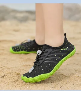 Kind trägt professionelle schwarz-grüne schnelltrocknende Wasserschuhe am Strand
