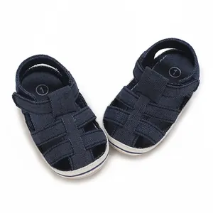 Dettaglio di sandali per neonati in denim blu navy con suola morbida traspirante.