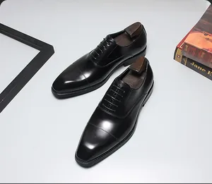 Chaussures richelieu élégantes en cuir noir pour hommes avec embauchoirs en bois sur table.
