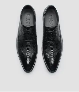 Dettaglio dall'alto di scarpe eleganti da uomo in pelle nera con stampa coccodrillo