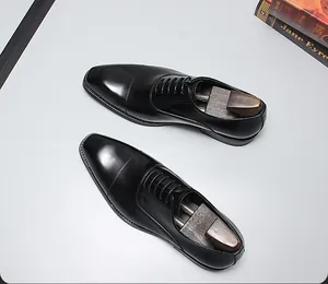 Vue de dessus des chaussures Oxford en cuir noir poli avec embauchoirs en bois.