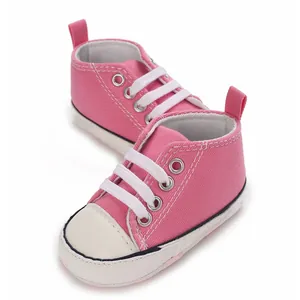 Nahaufnahme von rosa hohen Baby-Leinenschuhen mit weißen Schnürsenkeln und weichen Sohlen.