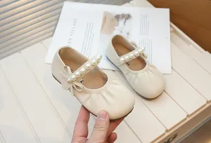 Detail of girls' cream Mary Jane shoes featuring pearl straps and bow accents