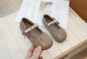 Detailed view of taupe vintage children's Mary Jane shoes with pearl strap and bow.