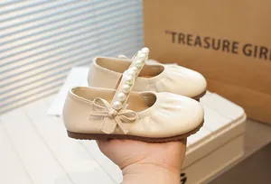 Detail of vintage beige Mary Jane shoes with pearl strap and bow for little girls