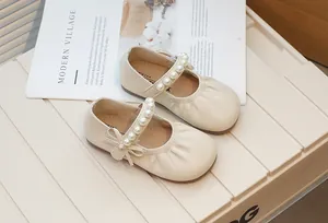 Detail view of cream girl's Mary Jane shoes with pearl strap and bow