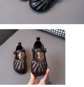 Detalle de zapatos Mary Jane marrones plisados para niñas con suelas blandas y correas.