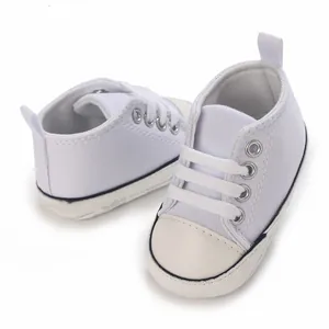 Nahaufnahme von weißen Leinwand-Babyschuhen mit weichen Sohlen für Kleinkinder.