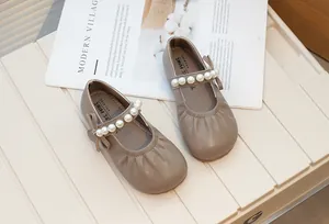 Detailed view of taupe girl's Mary Jane shoes with pearl strap and bow