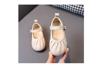 Primer plano de zapatos de princesa beige para niñas con punta plisada y hebilla