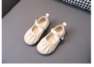 Detalle de cerca de zapatos tipo merceditas crema para niña con diseño plisado frontal