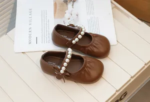 Elegant brown children's Mary Jane shoes featuring a pearl strap and delicate bow detail