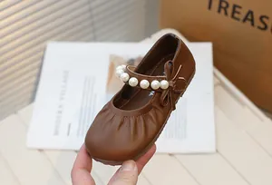 Close-up of brown Mary Jane girls' shoes with stylish pearl strap and bow detail