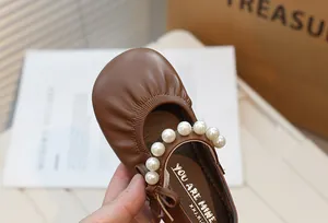 Detailed close-up of brown children's Mary Jane shoes with an elegant pearl strap