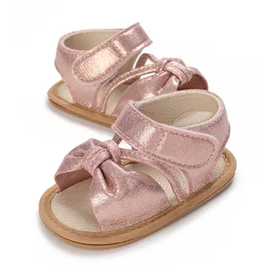 Detailed view of pink baby girl sandals with glittery finish and charming bow detail.
