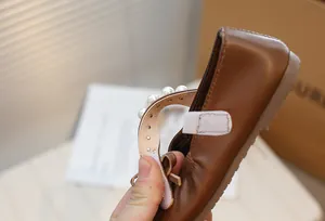 Close-up of brown Mary Jane girls shoes featuring an elegant pearl strap detail