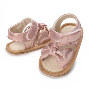 Detail view of pink sparkling baby girl sandals with decorative bow and velcro strap.