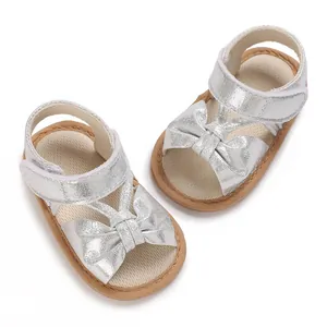 Detailed view of shiny silver baby girl walking sandals featuring a bow and soft non-slip sole.