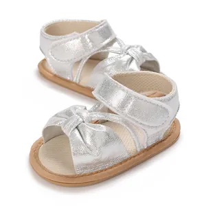 Detail view of silver metallic baby girl sandals with bow design and velcro strap.