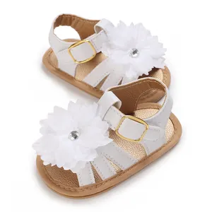 Primer plano de sandalias de princesa para bebé blancas con un gran detalle floral