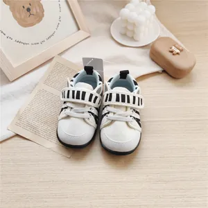 Detailed view of baby walking shoes with soft soles and striped Velcro straps info