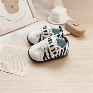Close-up of baby zebra-striped walking shoes with cute ear details on a wooden background.