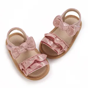 Detailed view of pink glittery baby sandals with decorative bows and ruffles