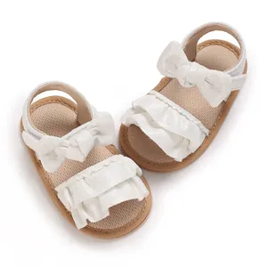 Detail view of white ruffled baby sandals with bows and soft anti-slip soles for summer