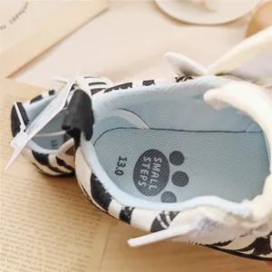 Close-up of zebra pattern baby walking shoes with soft blue mesh lining and paw print logo