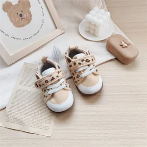 Cute leopard print infant soft-sole walking shoes displayed on a rustic wooden background