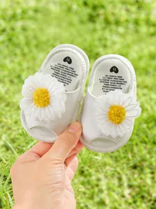Détail de sandales souples blanches pour bébé avec d'adorables fleurs de marguerites