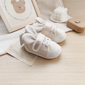 Macro view of beige baby walking shoes featuring cute plush bunny ears and soft soles.