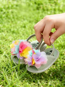 Gros plan de sandales pour bébé vert sauge avec décorations de marguerites colorées