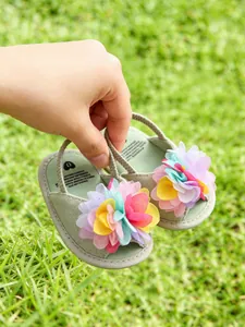 Détail des jolies sandales bébé vert sauge avec des fleurs de marguerite colorées