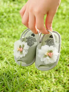 Gros plan de sandales vertes pour bébé avec dentelle florale et boutons de rose