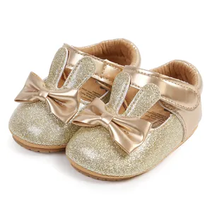 Detailed view of gold glitter baby shoes with bunny ears and metallic bows.