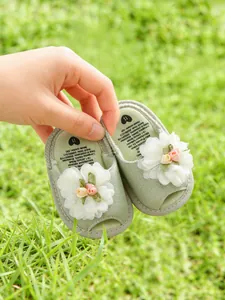Vue détaillée de sandales pour bébés vert clair ornées de marguerites en tissu blanc